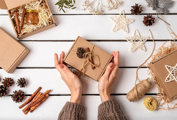 A woman is packing gifts in a craft box. Eco friendly Christmas. Wasteless