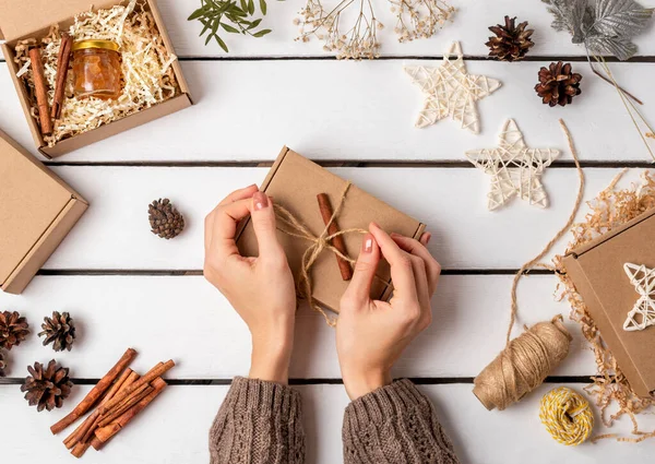 Bir kadın hediye kutusunda hediye paketliyor. Çevre dostu Noel. İsrafsız