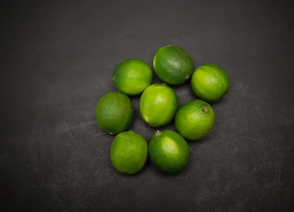 Closeup view of fresh appetizing green limes on dark grey background — Stock Photo, Image