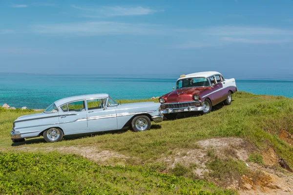 Nice view of old vintage classic retro cars standing above the ocean on a green gliff — Stock Photo, Image