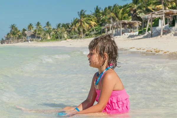Onnellinen pieni tyttö istuu taivaansininen rauhallinen valtameri aurinkoinen upea trooppinen ranta — kuvapankkivalokuva