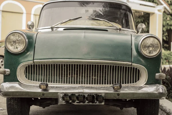 Vista frontal de un viejo coche clásico retro vintage contra fragmento de fondo de jardín tropical —  Fotos de Stock