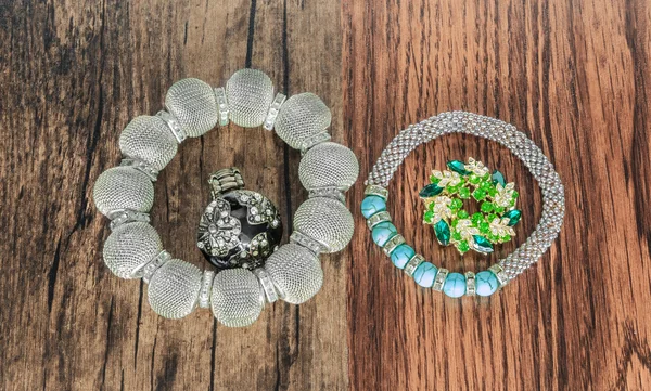 Berbagai macam gelang bergaya bros dan cincin terisolasi pada latar belakang kayu vintage tua — Stok Foto