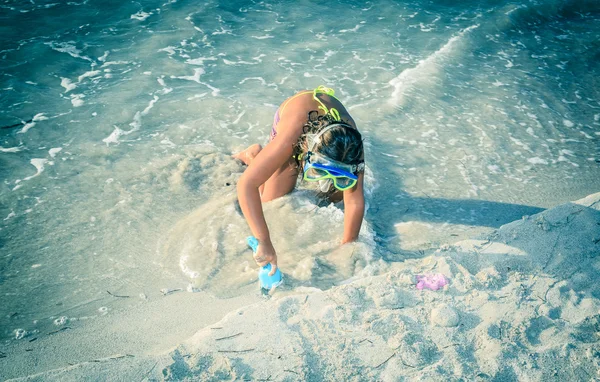 Bambina che gioca nella sabbia sulla spiaggia vicino all'oceano — Foto Stock