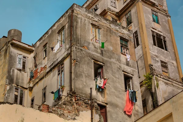 Velho vintage degraiding edifício pobre com várias roupas penduradas fora das janelas abertas — Fotografia de Stock