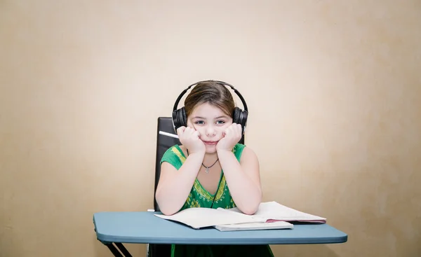 Küçük güzel kız notebook ve kulaklık ile sınıfta kafasındaki masanın konsantre