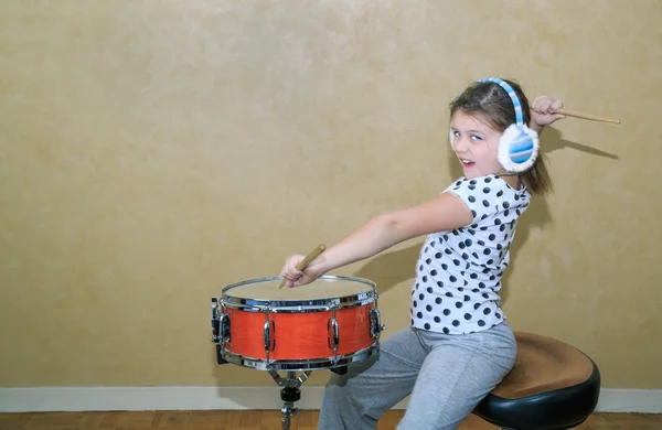 Divertente stile bambina in movimento pratica su rullante tamburo in studio stanza contro vintage parete sfondo — Foto Stock