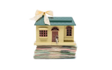 Para banknot beyaz arka plan karşı yığını üzerinde küçük minyatür ev modeli duran