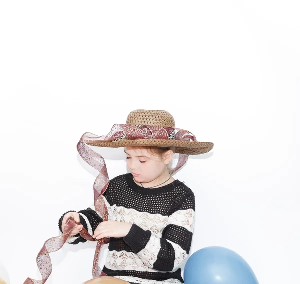 Elegante bambina concentrata sulla decorazione del suo cappello alla moda con un nastro — Foto Stock