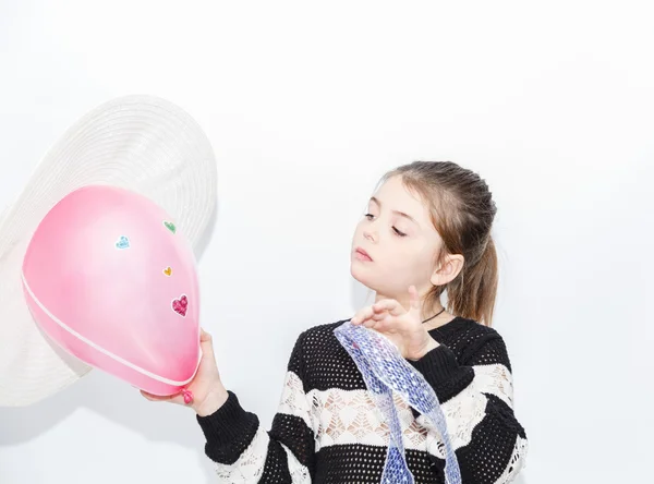 Snygg koncentrerad liten flicka tittar på rosa ballong maded för alla hjärtans dag — Stockfoto