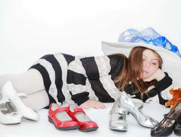 Gestylte hübsche kleine Mädchen liegen und genießen ihre Freizeit durch die Wahl eines neuen Schuhen zu tragen — Stockfoto