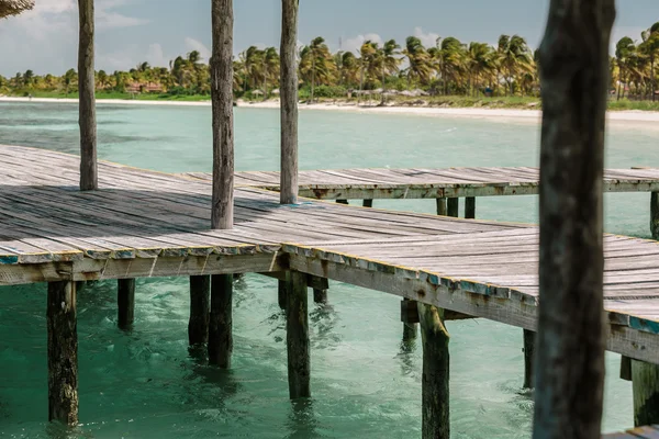 Wooden deck standing in tranquil ocean against beautiful inviting tropical beach — Stock Photo, Image