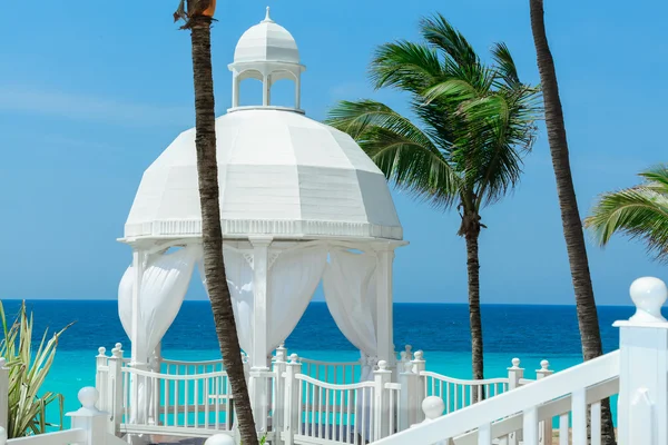 Beautiful cozy inviting  white gazebo standing against azure turquoise ocean and blue sky — Stock Photo, Image