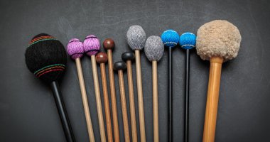fragment of view of  hand made  drum and percussion orchestra natural hickory wood sticks on dark grey