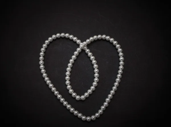 Gorgeous  amazing white pearl fashionable jewelry, necklace shaped as valentine heart on dark grey background — Stock Photo, Image