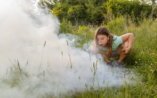 Child girl trying to blow fire to a blaze — Stock Photo, Image