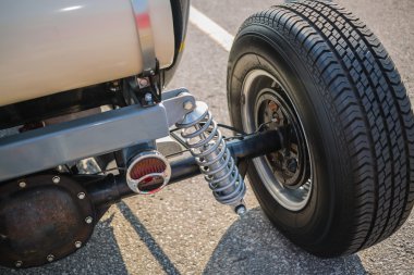 Rear view of old vintage customized hot rod car wheel and other parts