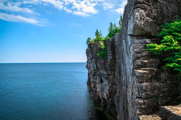 View of big long rocky cliff standing in Cyprus lake against blue bright sky at beautiful gorgeous Bruce Peninsula, Ontario — ストック写真