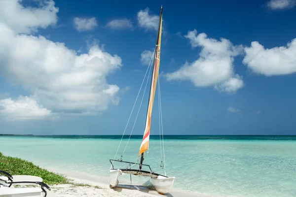 Amazing view of sailboat resting on white sand Cuban beach on background of bright tranquil turquoise ocean water and deep blue sky — Zdjęcie stockowe