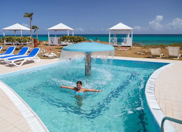 улыбаясь счастливая маленькая девочка наслаждаясь отдыхом, купаясь и расслабляясь в бассейне с природной морской водой
