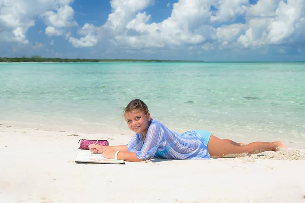 Smiling joyful happy little girl relaxing on white sand beautiful beach against ocean and blue sky background — Stok fotoğraf