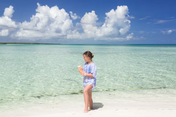 Pretty styled cute little girl walking along the beach and tranquil beautiful ocean , holding bread in her hands — Stok fotoğraf