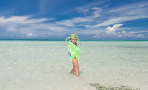 Beautiful stylish happy joyful little girl standing in tranquil turquoise ocean on beautiful blue sky background — Zdjęcie stockowe