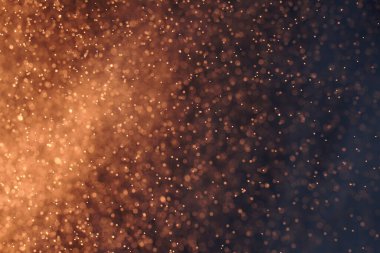 Seçici odaklı soyut şenlik arkaplanı. Parlak sarı parçacıklar, koyu arkaplan. Sıçramalar, uzay enerji akışı