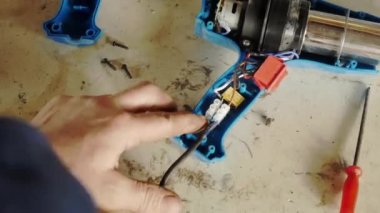 Bir adam çalışan bir saç kurutma makinesini tamir eder.