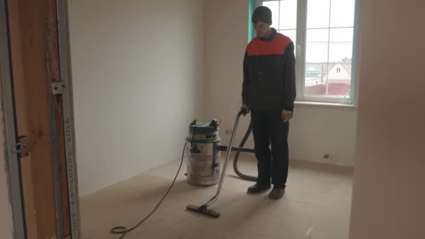 Работник пылесосит комнату рабочим пылесосом — стоковое видео