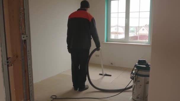 Работник пылесосит комнату рабочим пылесосом — стоковое видео