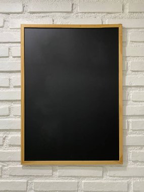 Siyah kağıt tahta, beyaz tuğla duvarda asılı duruyor.