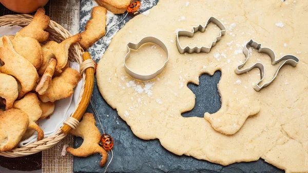 Making cookies for Halloween. Cut out cookies from dough in the form of pumpkin, cat, ghost and bat.