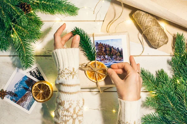 Doğuştan kaba kağıt, kenevir ipi, ladin dalları, antika makas gibi çevre dostu dağların fotoğraflarıyla dolu Noel hediyeleriyle dolu kadınların elleri. Hediye olarak seyahat et..