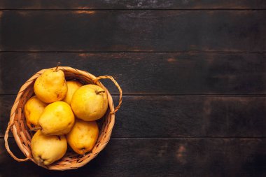Koyu ahşap arka planda sepeti kusurlu doğal armut meyvesi..