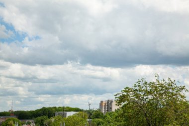 Mavi gökyüzünde beyaz bulutlar ve ağaçlar. Metin arkaplanı için alanı olan düz beyaz bulutlu açık mavi gökyüzü.