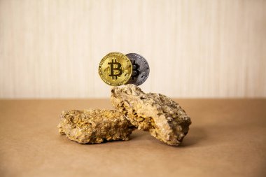 Golden Bitcoin Coin balances on natural stones on light background. Blockchain cryptocurrency, store of value.