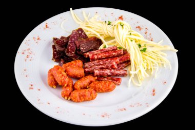 Bira aperatifi: Cecil peyniri, picolini sosisi, sujuk, jorki. Siyah arka planda izole edilmiş lezzetli tütsülenmiş sosis tabağı.