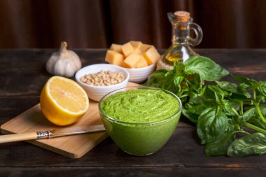 Evde pesto sosu yapma süreci. Kadın sos yapmak için havana fesleğen yapraklı zeytinyağı döküyor..
