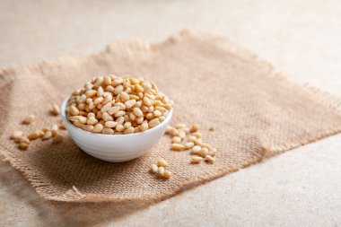 Arka planda jüt peçetede bir kasede organik çam fıstığı. Yakın plan.