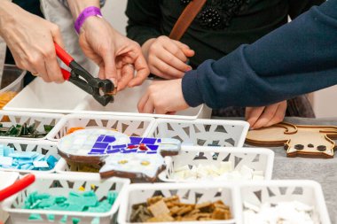 Çocuklar için mozaik paneller yapma konusunda yüksek lisans. Bir cam ve çocukların ellerini kesen bir ustanın elleri.