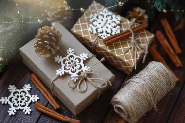 Yaratıcı sıfır israf Noel konsepti, sicimle bağlanmış el yapımı hediye kutuları, altın köknar kozalakları ve ahşap kar taneleri ve tarçın çubukları.