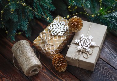 Yaratıcı sıfır israf Noel konsepti, sicimle bağlanmış el yapımı hediye kutuları, altın köknar kozalakları ve ahşap kar taneleri ve tarçın çubukları.