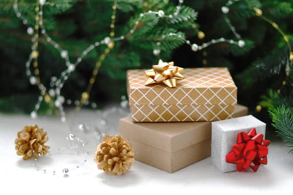 Vánoční dárky a dárkové krabice zabalené v kraftovém papíru na dřevěném stole se zlatými jedlemi, větvemi jedlí a dekoracemi. Nový rok, vánoční koncept. — Stock fotografie