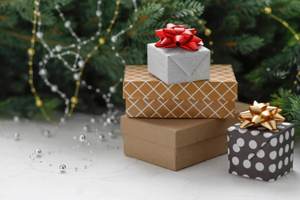 Noel hediyeleri ve hediye kutuları ahşap bir masanın üzerinde altın köknar kozalakları, köknar ağacı dalları ve süslemelerle sarılı. Yeni yıl, Noel konsepti. 