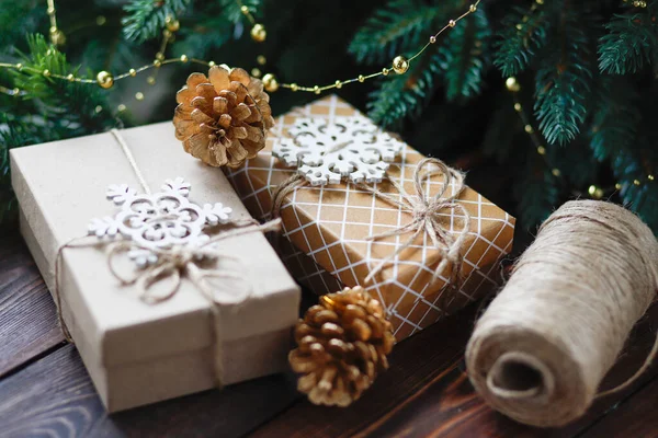 Креативні нульові відходи Різдвяна концепція, подарункові коробки ручної роботи, пов'язані шпагатом, з золотими ялиновими шишками та дерев'яними сніжинками та паличками кориці — стокове фото