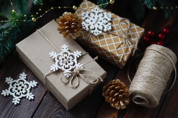 Kreativ noll avfall jul koncept, handgjorda presentförpackningar bundna med garn, med gyllene gran koner och trä snöflingor och kanel pinnar — Stockfoto