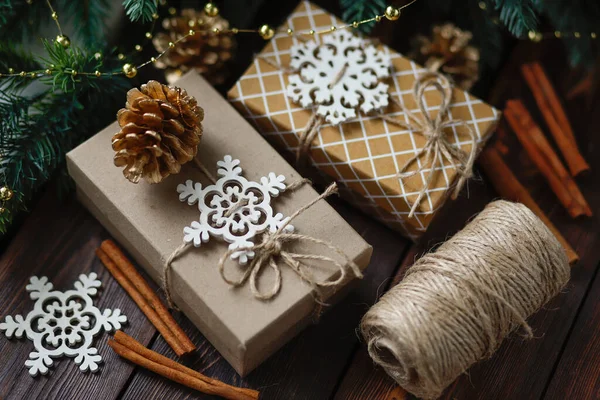 Creative zero waste Christmas concept, handmade gift boxes tied with twine, with Golden fir cones and wooden snowflakes and cinnamon sticks — Stock Photo, Image