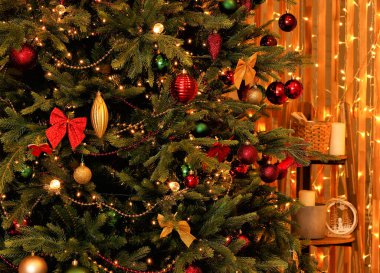 Noel ağacı parlak Noel oyuncakları, yaylar, altın ve kırmızı çelenklerle süslenir.
