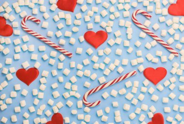 Marşmelov dokusu, baston şekerler ve mavi arka planda saten kalpler. Noel ve Sevgililer Günü konsepti